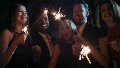 sexy group of friends at glamorous party lighting sparklers