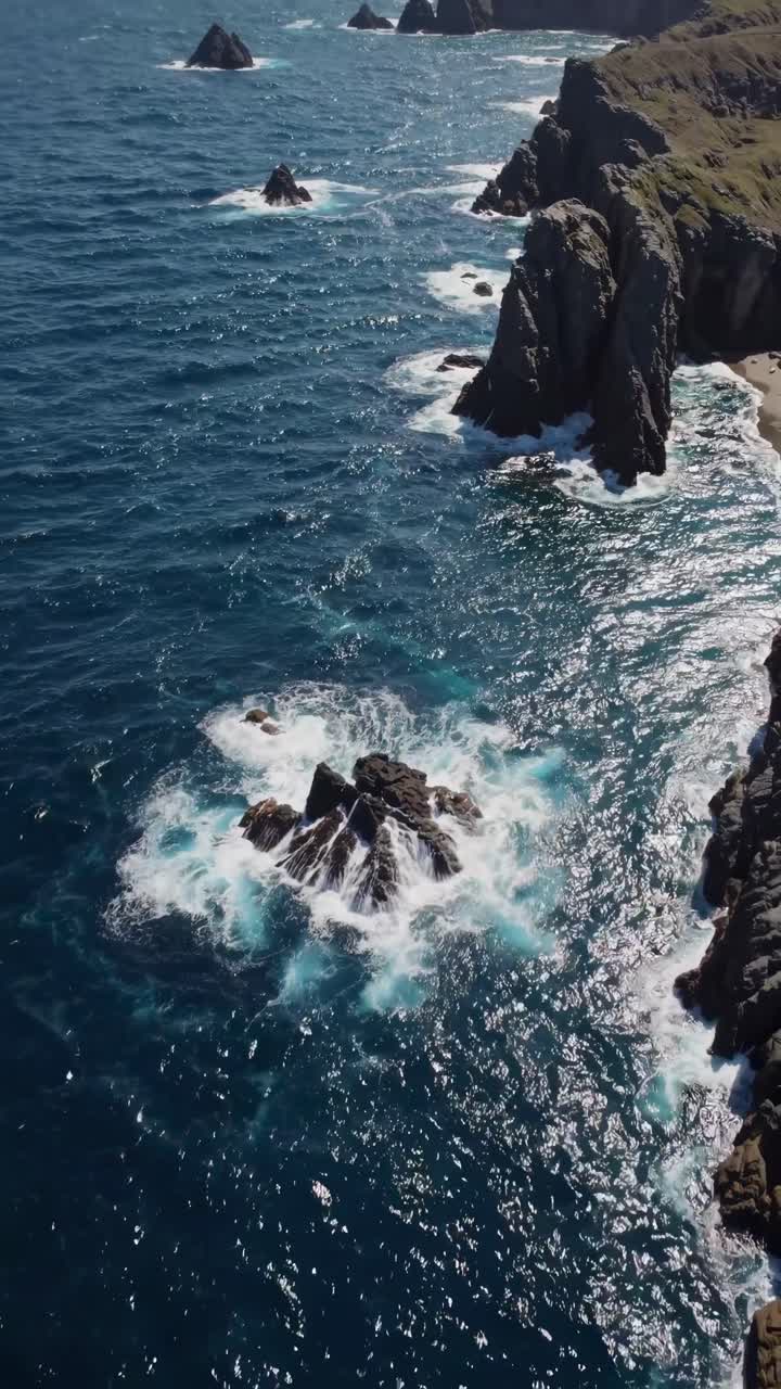 Un video aereo riprende scogliere frastagliate e onde impetuose dall'alto, mostrando il drammatico