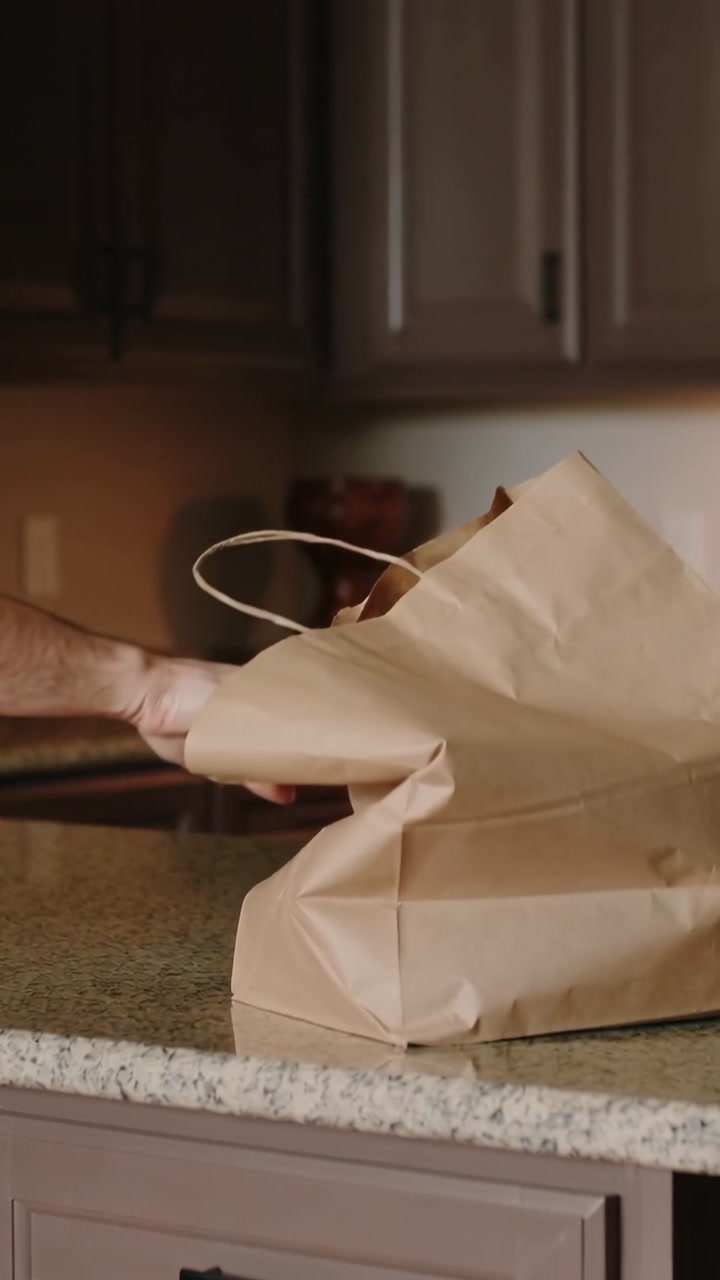 Hand Setting Down a Brown Paper Bag on a Kitchen Counter