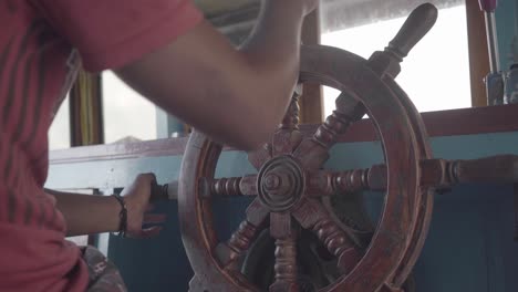 close view of an old wooden rudder of a boat being moved by the captain