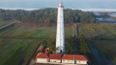 Aerial-footage-in-4k-of-flying-around-white-lighthouse-with-the-beach-on-the-background