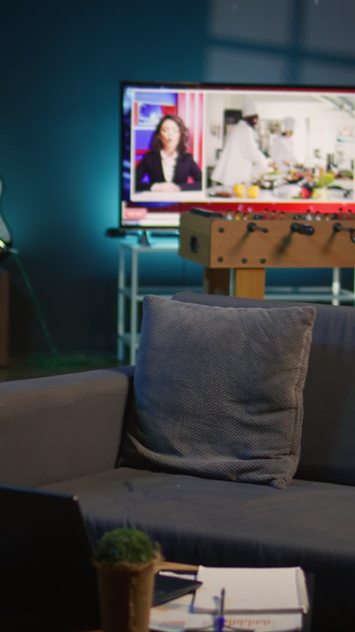 Soggiorno vuoto con divano, laptop e televisore che trasmette notiziari