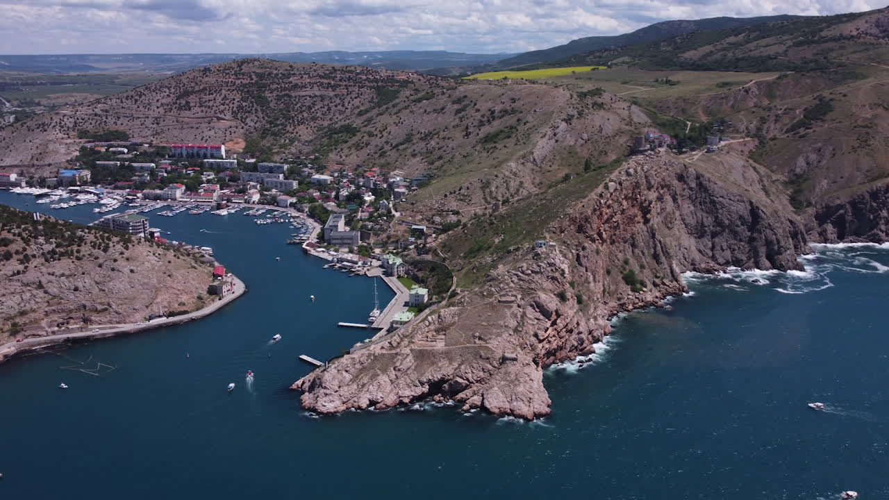 Aerial view of a coastal town and harbor with mountains
