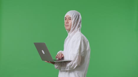 side view of asian male scientist typing on a laptop and looking around on green screen background