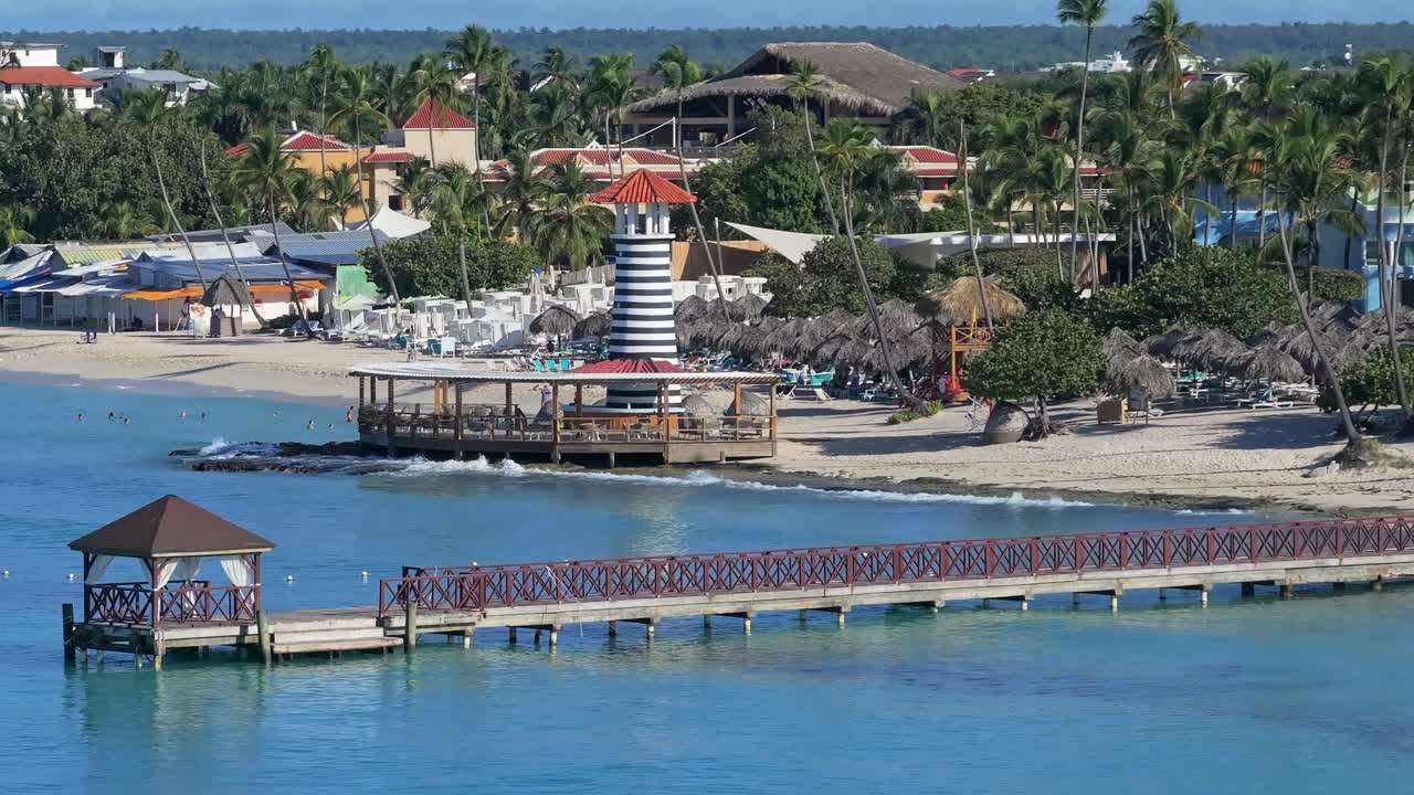 The wooden pier and lighthouse at Dominicus Beach, Bayahibe, the Dominican Republic. Drone aerial view, pan right