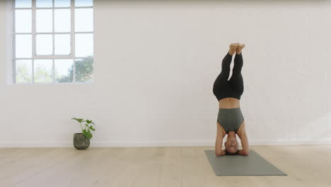 healthy yoga woman practicing headstand pose enjoying fitness lifestyle exercising in studio stretching beautiful body training on exercise mat