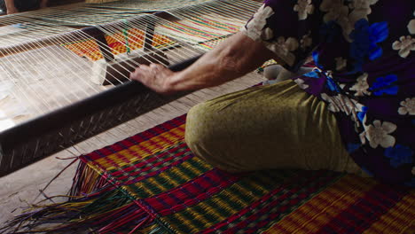 Close-up-shot-of-hands-of-senior-ladies-hand-making-a-traditional-mattress-in-Quang-Nam-province,-Vietnam-in-side-a-handloom