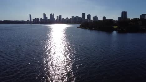 Drone-shot-rising-over-Swan-River-to-skyline-of-Perth,-Western-Australia-and-South-Perth-foreshore