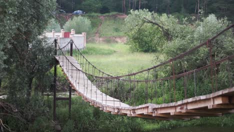 wooden suspension bridge over a river in a forest