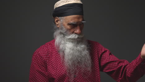 close up bajo clave de estudio de iluminación tiro de anciano sikh hombre plegable tela para turbante contra plano de fondo oscuro tiro en tiempo real 1