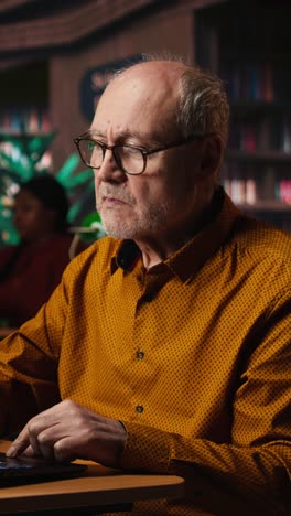 vertical video elderly male adult reviewing academic text on a laptop at the university