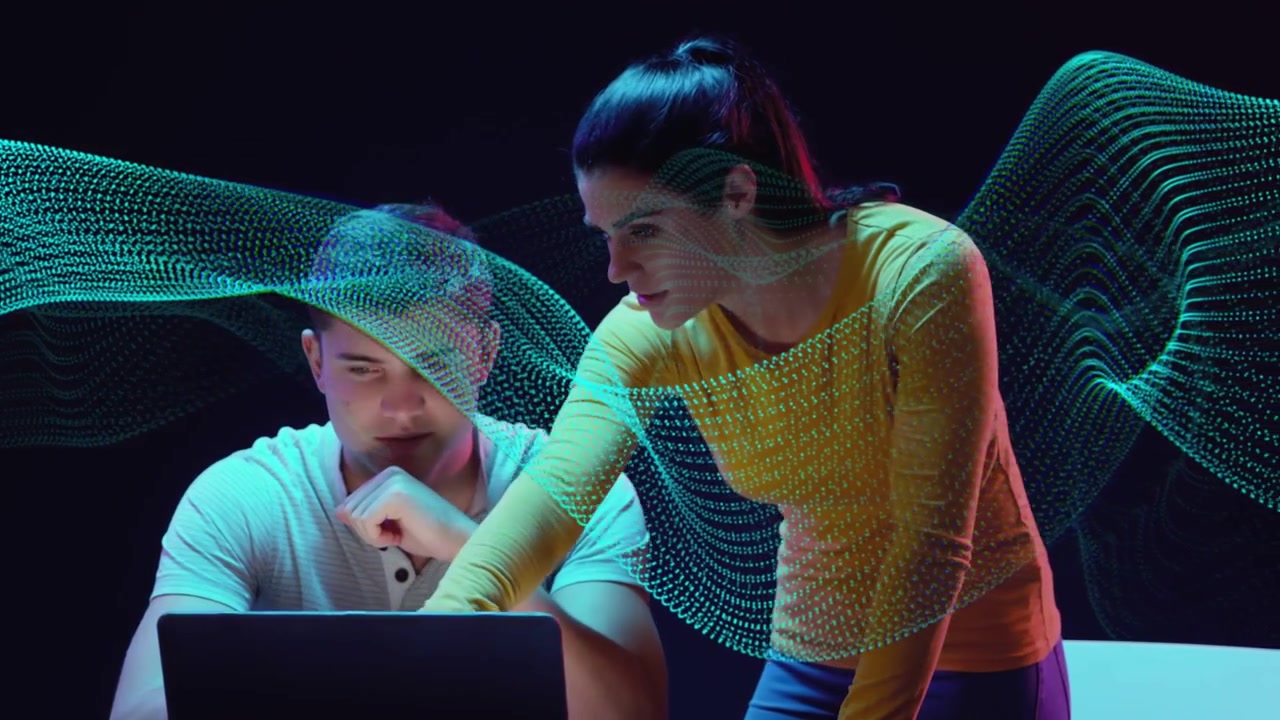 Man sitting laptop woman leaning and pointing starting teal wave around them guiding tech review