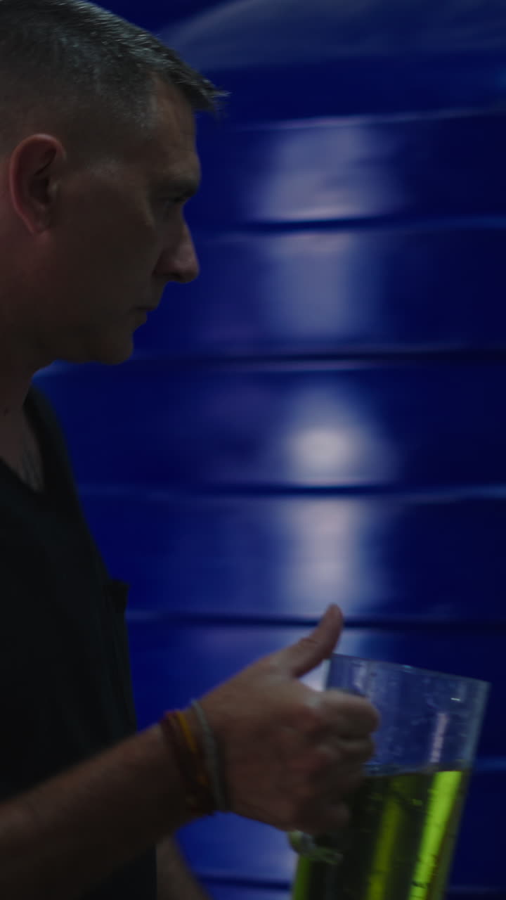 Uomo che versa un liquido verde in un contenitore industriale blu