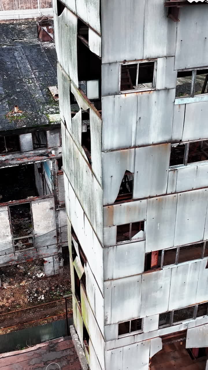 Old plant territory abandoned long ago. Grey wrecked skeletons of the industrial premises. View from above. Vertical video