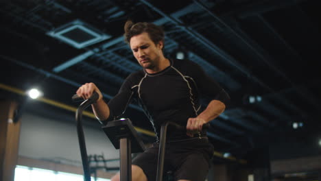 hombre deportivo enojado haciendo cardio en el gimnasio. hombre en forma ejercitándose en velosimulador