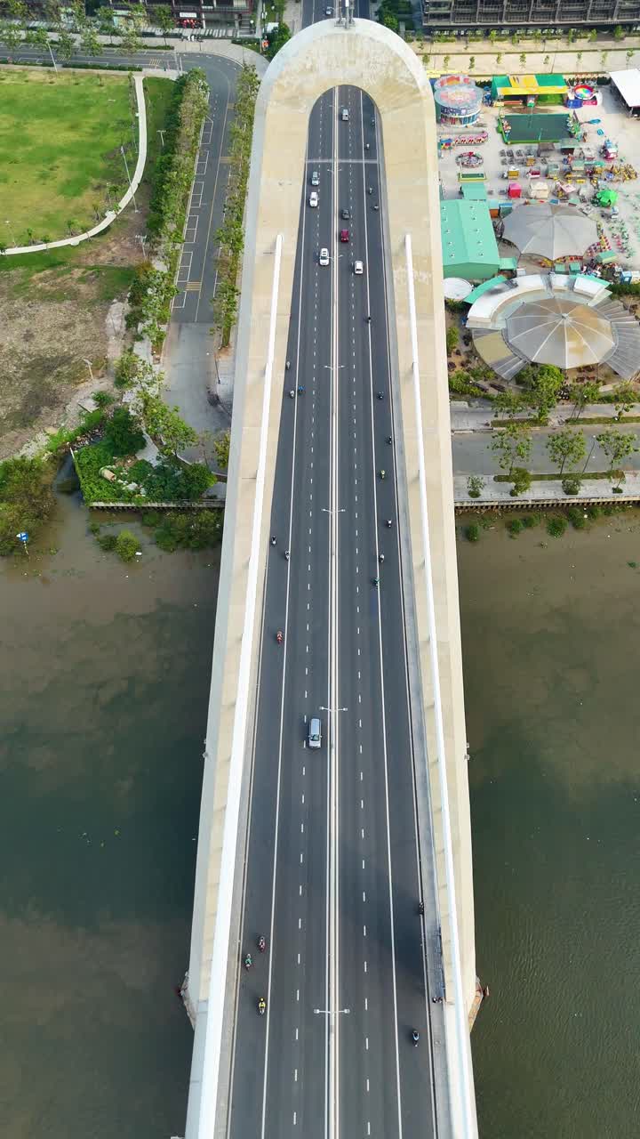 Vertical top-down aerial view of a wide bridge spanning the Saigon River in Ho Chi Minh City, with light traffic crossing over calm waters. Vietnam, UHD.