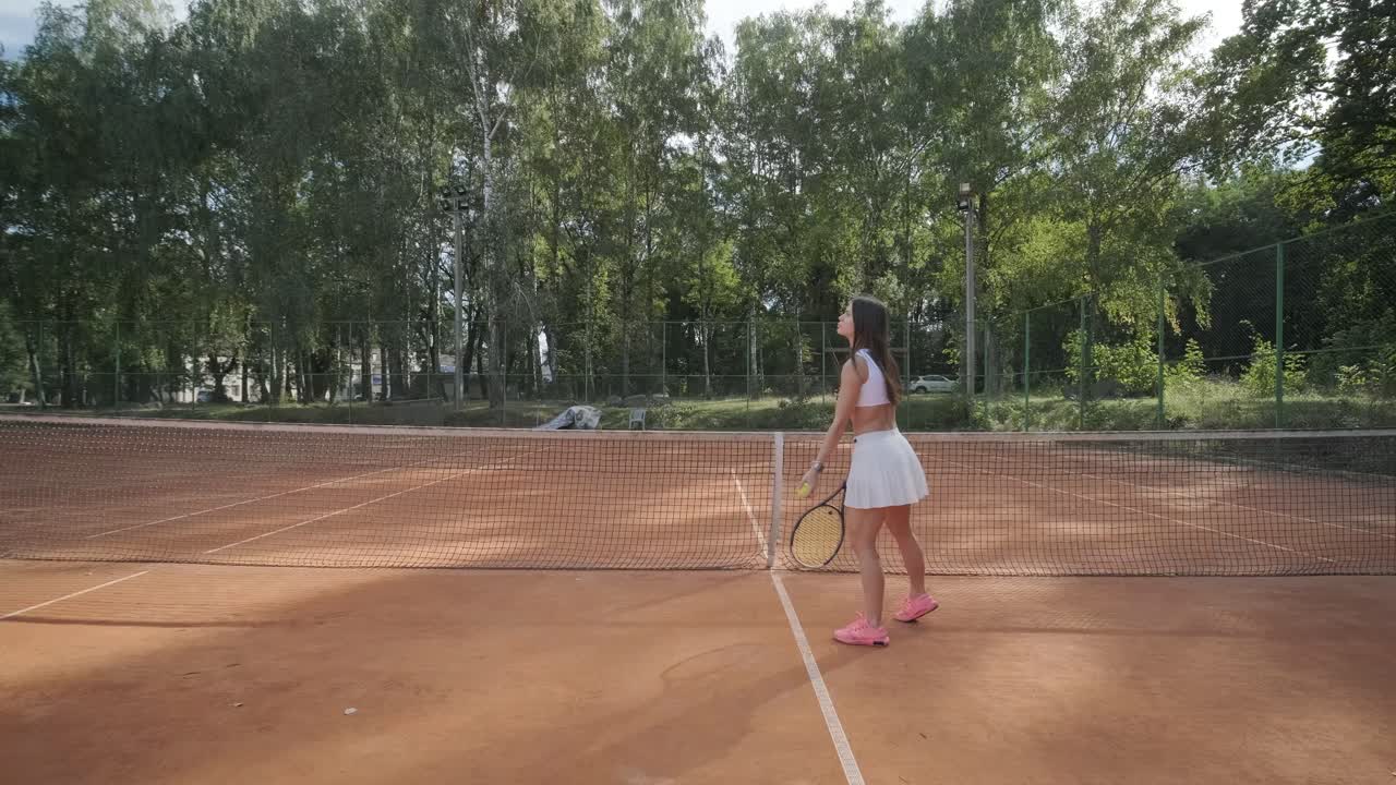 여자 테니스 선수 가 야외 코트 에서 세브 를 연습 하고 있다