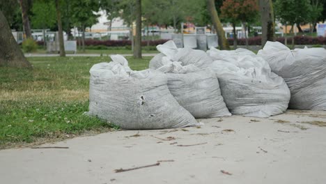 white trash bags filled with yard waste in a park