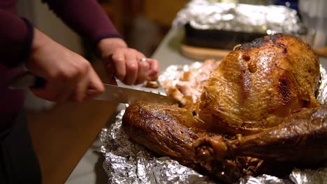 slicing a turkey's leg with a knife and a bear claw tool then putting it aside