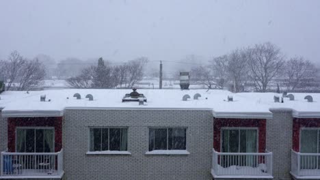 winter snow falls on urban brick apartment building with windows and balcony during day 4k