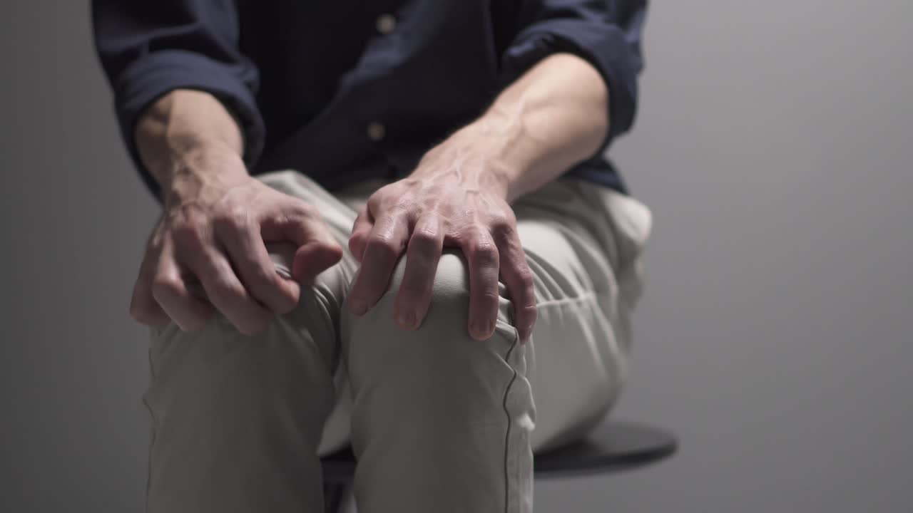 Un uomo è seduto su una sedia, nervoso. Sembra che stia avendo un attacco di panico