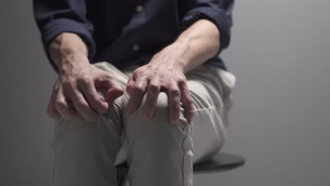 a man is sitting on a chair nervous. seems like he is having a panic attack.