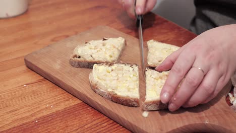 woman's hands cut two slices of bread with butter and garlic