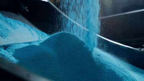 slow motion shot of blue polyethylene powder as it falls in the form of rain and forms a pile on a metal mold for rotomolding