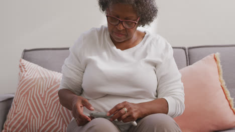 Senior-mixed-race-woman-using-a-smartphone.-Social-distancing-and-self-isolation-in-quarantine