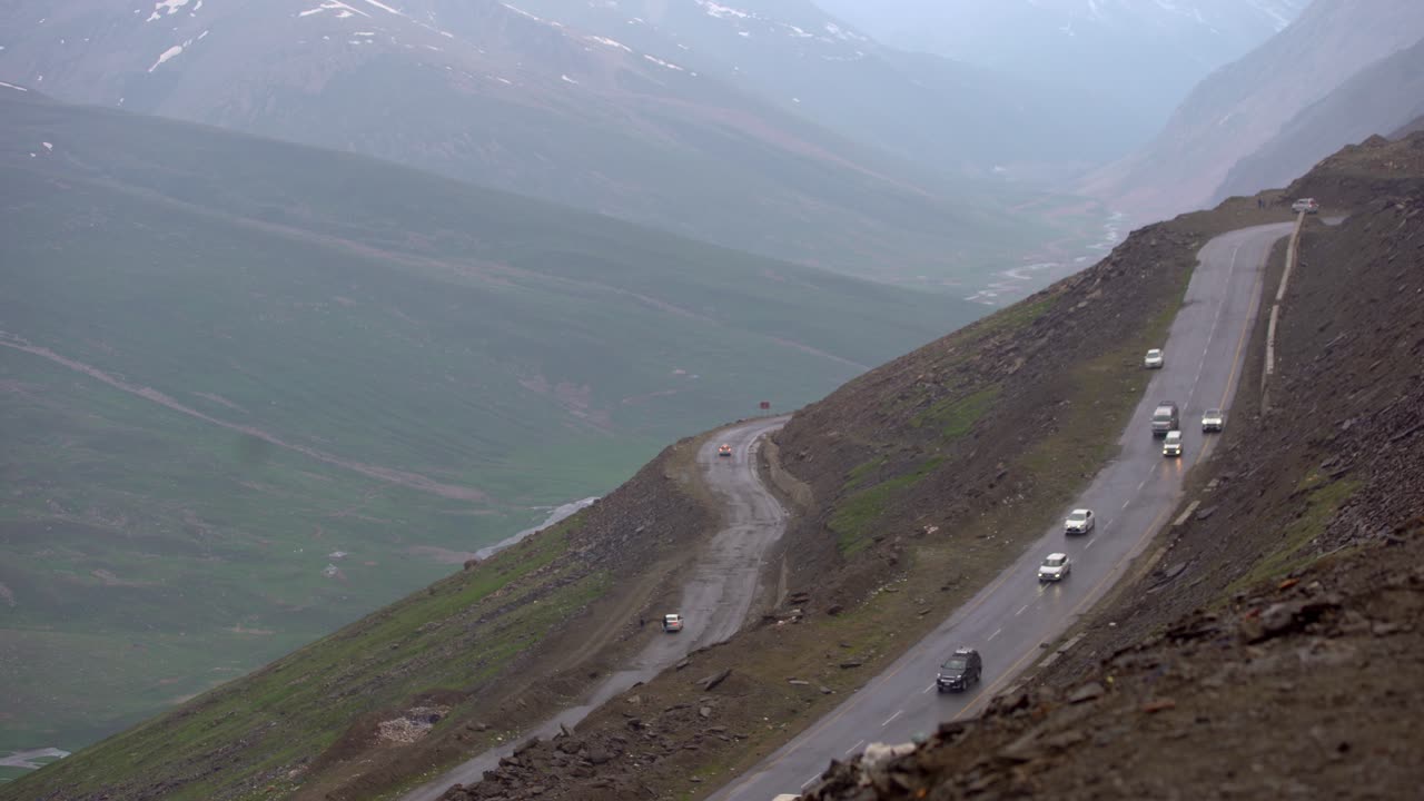 Foggy view of the Babusar valley, mountain pass in Pakistan, street with passing cars, static, copy space