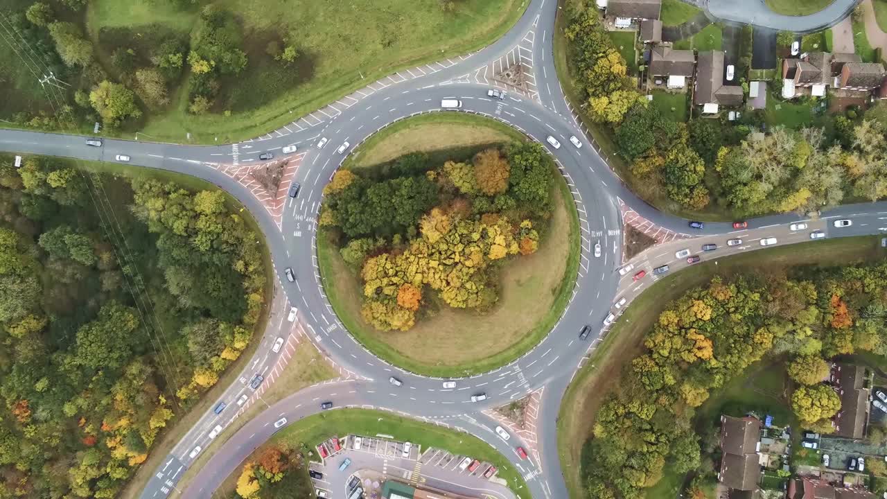 Aerial traffic rotating above urban roundabout traffic top down view