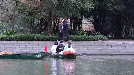 gente remando en un barco cerca de la orilla del río en ninh binh