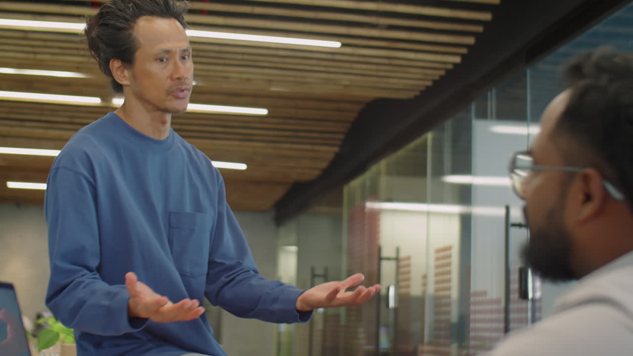 Asian Man Talking about Business with Colleague in Coworking Room
