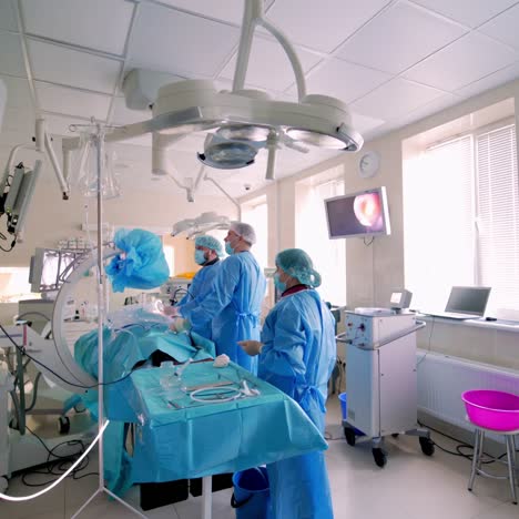 surgery in hospital. specialists providing operation with modern technology equipment in hospital. back view of doctors looking on monitor during operation. video