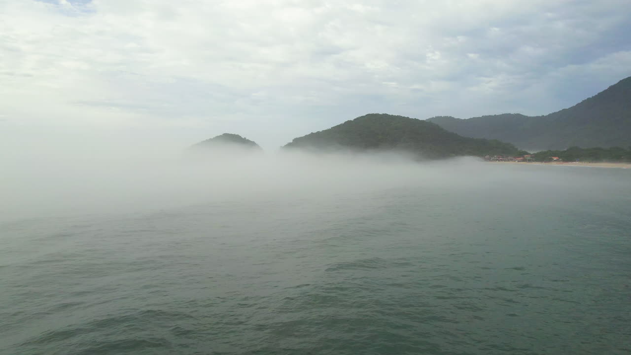 Aerial view flying low over the sea and through ocean mist on the coast of Brazil