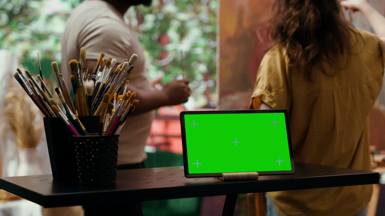 Kunstnere bruger tablet med grøn skærm i et kunststudie