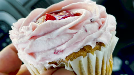 Hand-holds-delicious-cupcake-with-buttercream-frosting,-close-up-shot