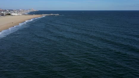 Luftaufnahme-Entlang-Der-Küste-In-Richtung-Einer-Hütte-Auf-Einem-Dock-An-Einem-Schönen-Strand-An-Einem-Sonnigen-Tag