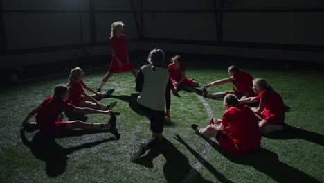 girls soccer team stretching during indoor practice