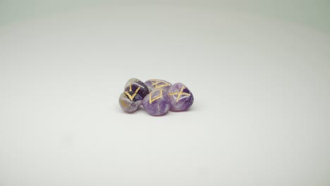 piedra morada cara con una marca amarilla diferente en la parte superior girando sobre la mesa - toma de primer plano
