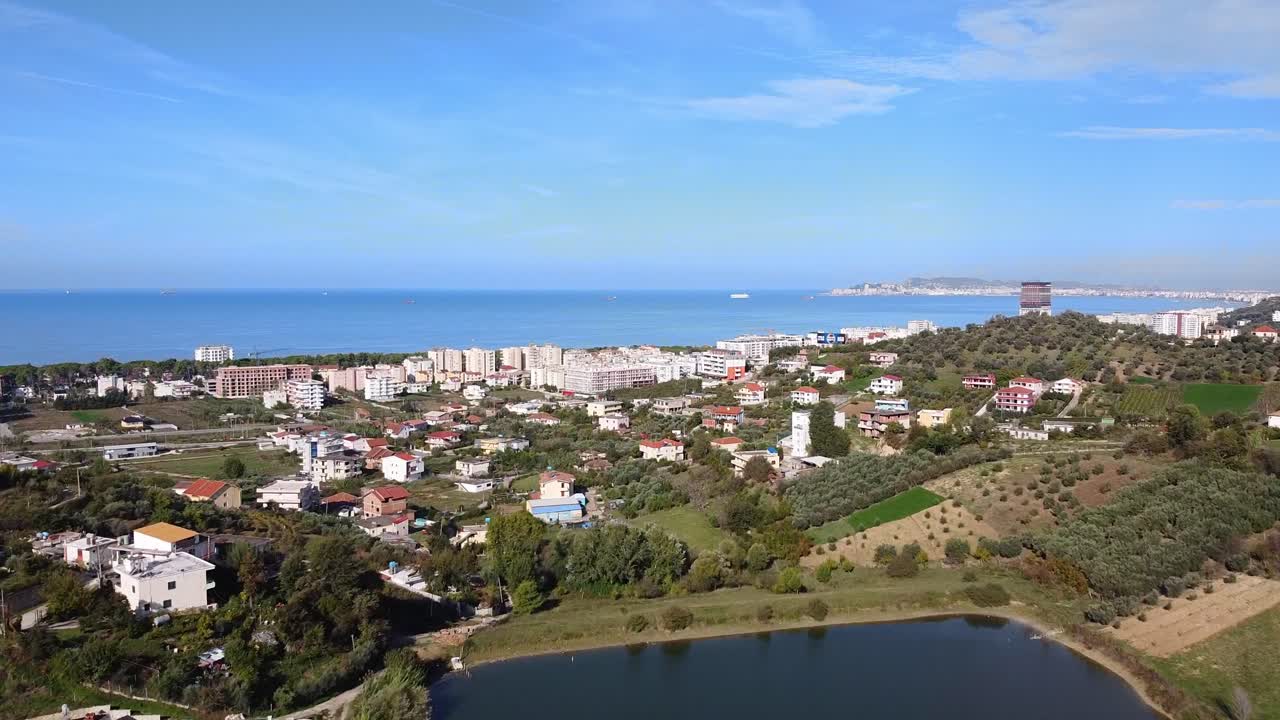 Aerial above coastal town in Albania. agricultural fields and hotel buildings view.