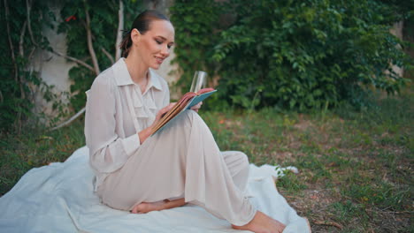 una mujer sonriente disfruta de una novela en un picnic de verano en el jardín verde.