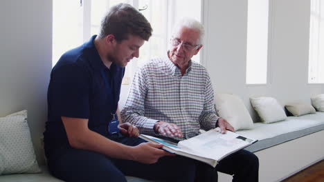 male nurse and senior man looking at a photo album together