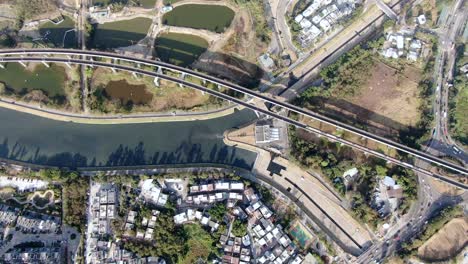 Hong-Kong-outskirts-MTR-city-tram-crossing-a-bridge,-Aerial-view