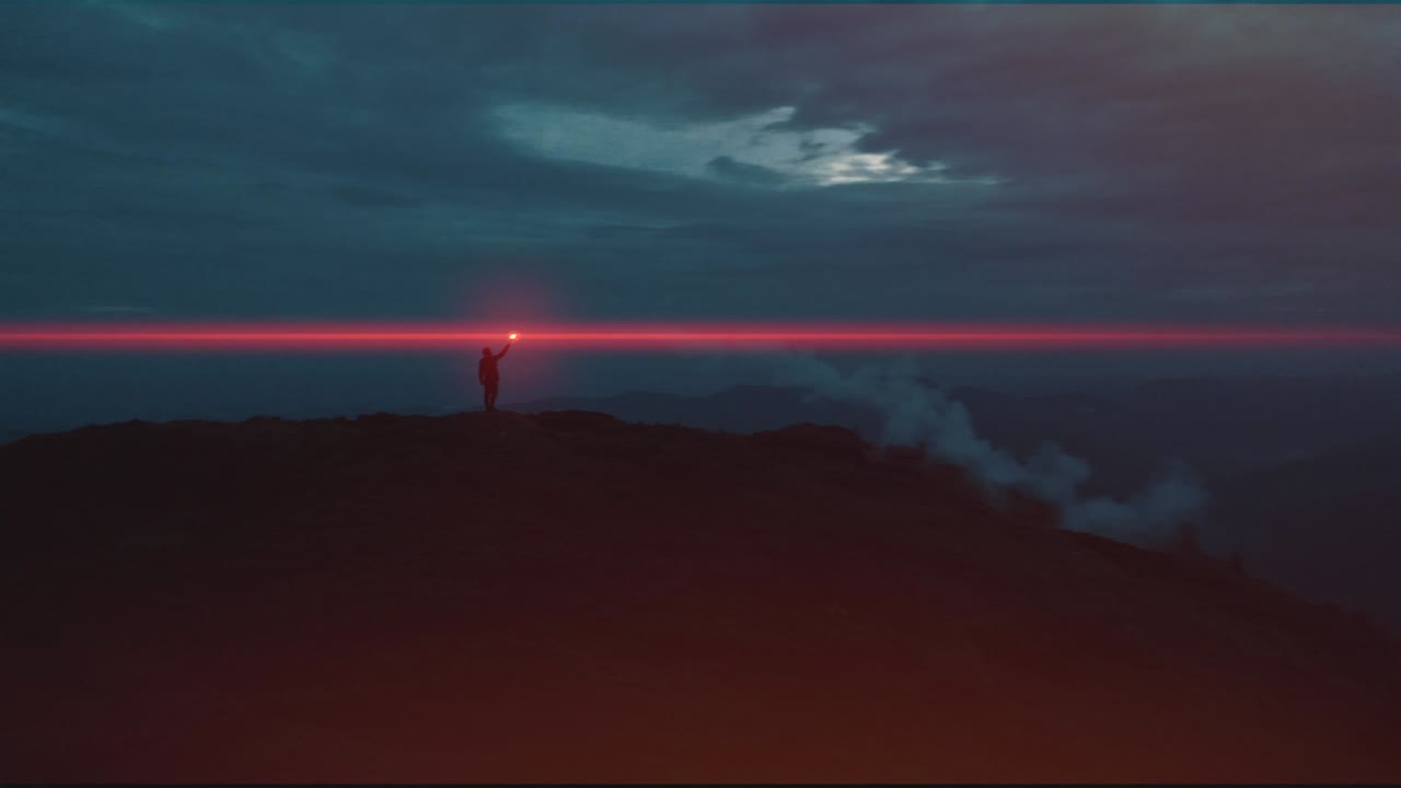 el hombre sostiene un palo de fuego rojo en la cima de la montaña