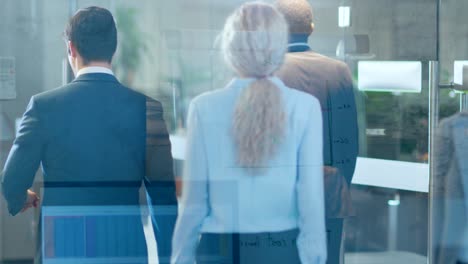 through the glass shot of resolute business people walking through the corporate building hallway.