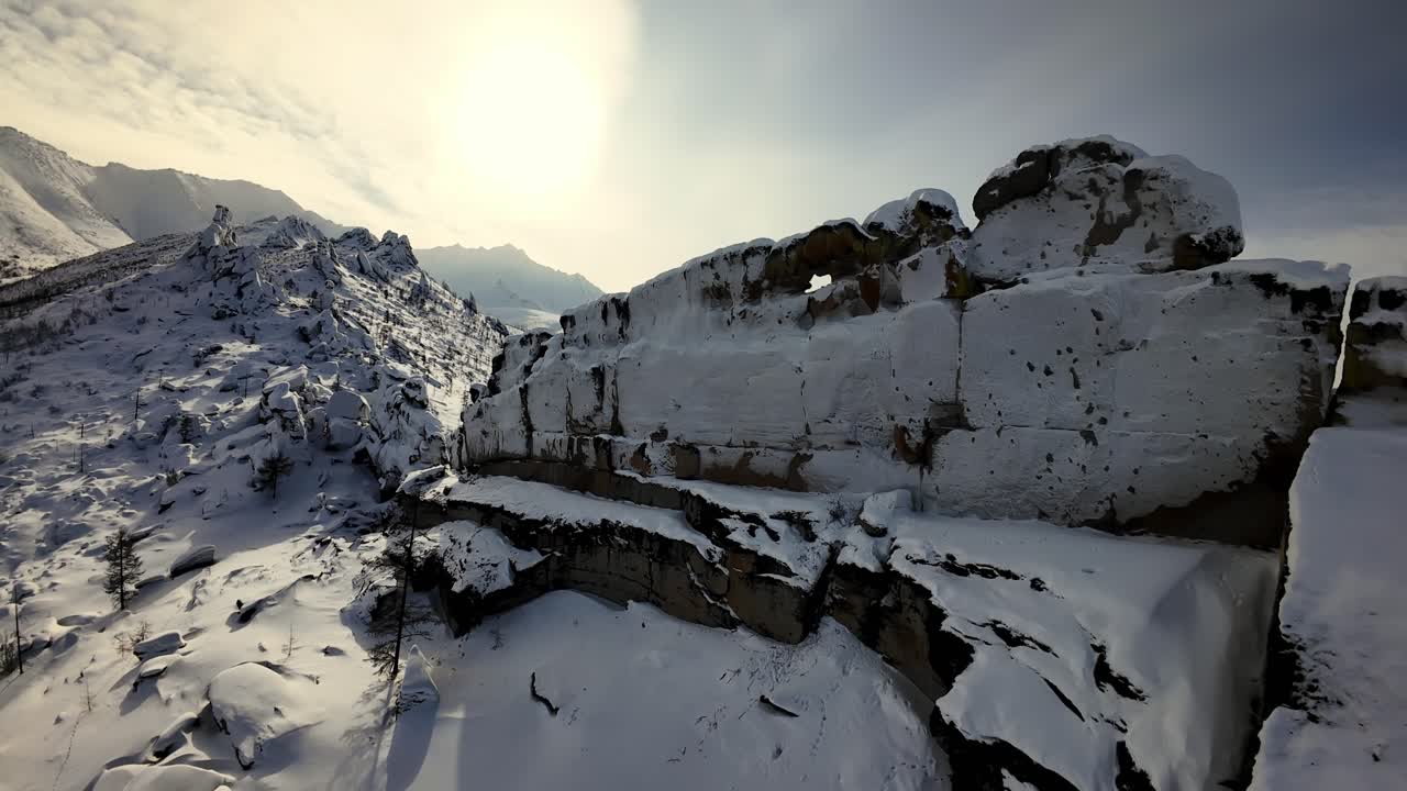 Kayalık arazi üzerinde drone uçururken karlı bir dağ manzarasını keşfetmek.