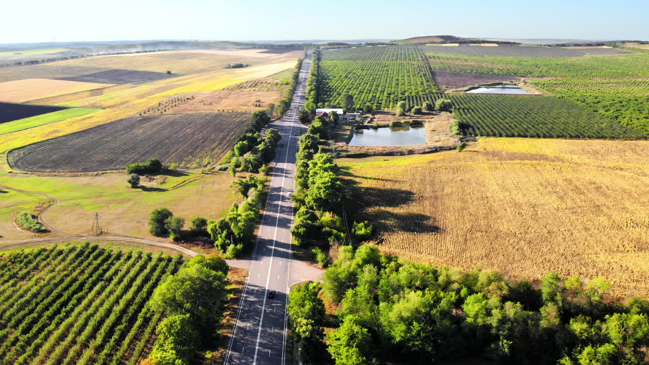 Aerial drone view of a road with moving car in highland. Green fields and hills from north part of Moldova
