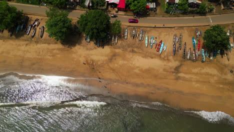 Von-Oben-Aufgenommene-Drohne-Eines-Ruhigen-Strandes-Mit-Fischerbooten-Und-Einer-Afrikanischen-Stadt