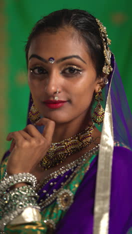 vertical video close up portrait of female kathak dancer performing dance wearing traditional indian dress and jewellery looking at camera 2